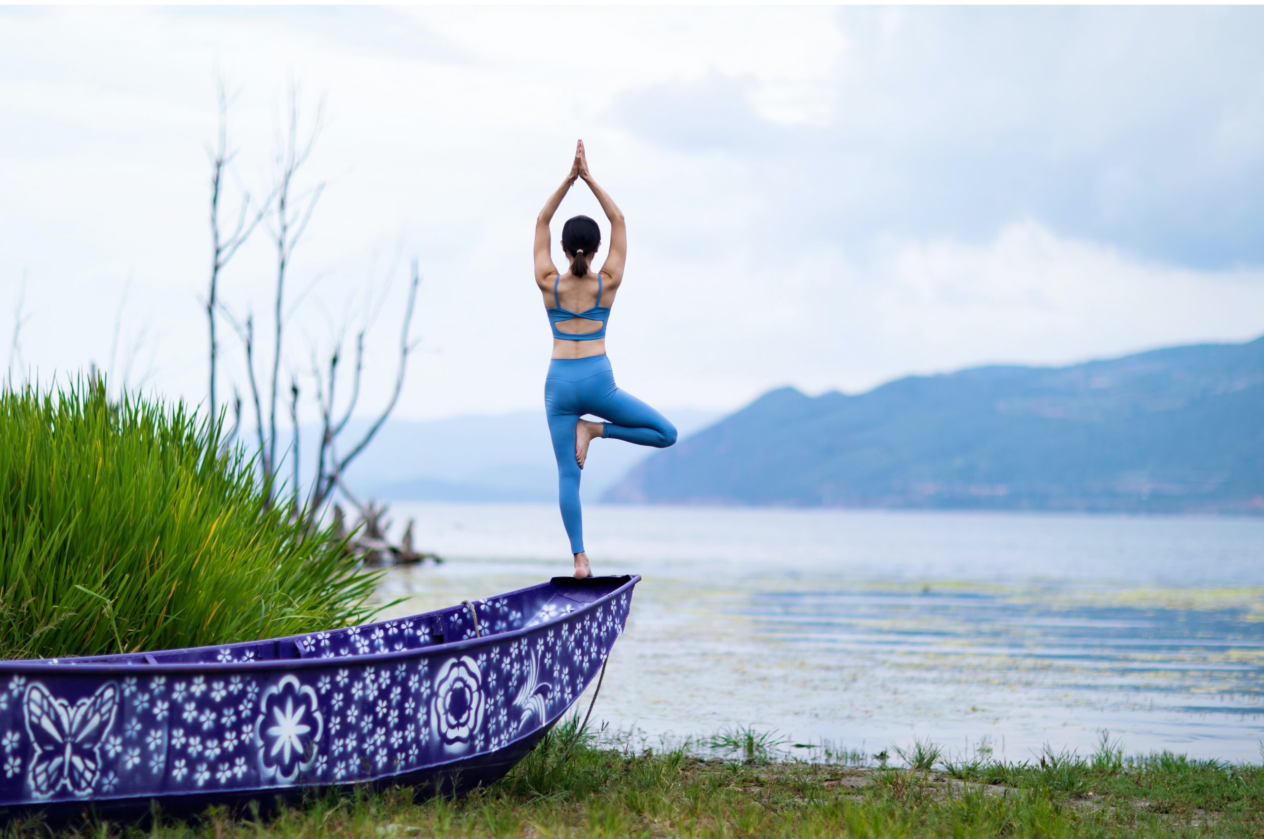 ženska v joga pozi na robu čolna, pred jezerom